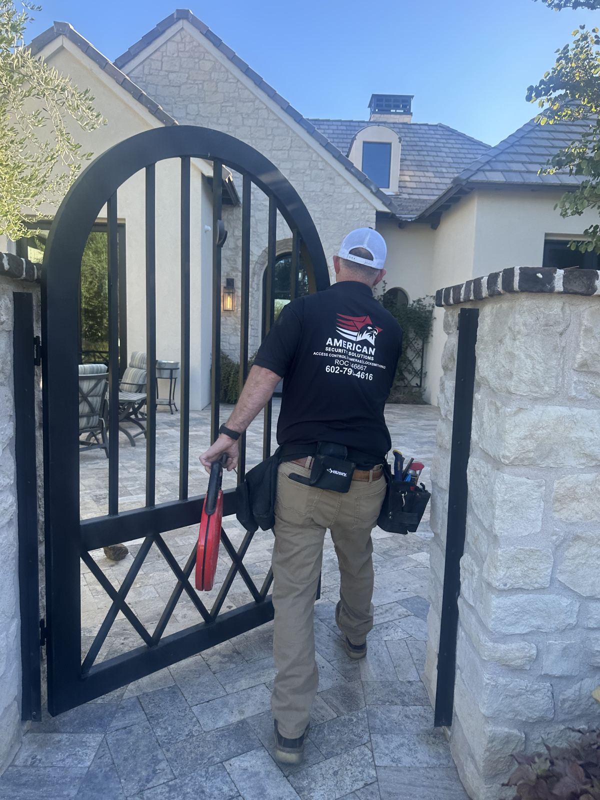 Technician walking through a custom iron gate at a home with access control