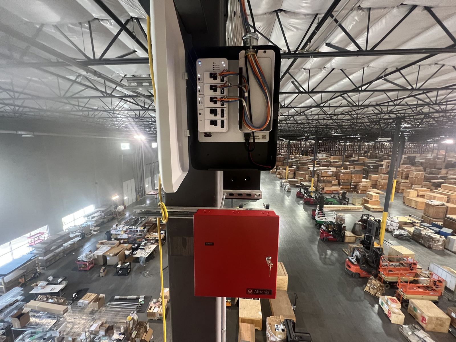 Security equipment enclosure mounted high on a column inside a large warehouse